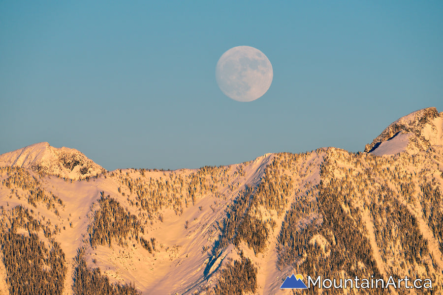 supermoon rising above snow covered purcell mountains at sunset